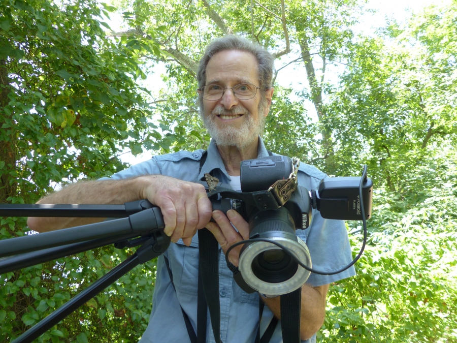 Ron Goor ’62 holding a camera with a butterfly resting on it